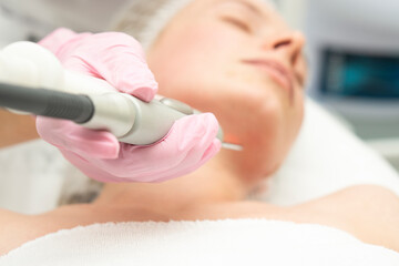 Doctor cosmetologist makes a laser dermal rejuvenation procedure to a patient. Against the...