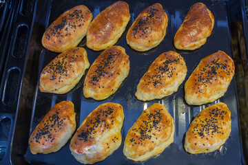 Homemade pastries that are brushed with egg yolk and sprinkled with black cumin. selective focus. on the baking tray