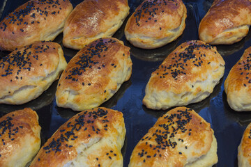 Homemade pastries that are brushed with egg yolk and sprinkled with black cumin. selective focus. on the baking tray