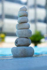 Colorful stones stacked on top of each other in harmony on the edge of the pool. Selective Focus Stones.