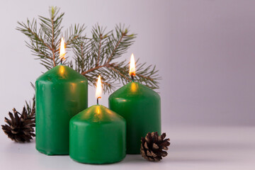 Festive burning green candles with fir branches