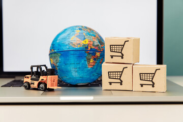 Globe model with wooden boxes on a laptop. Online shopping and delivery concept