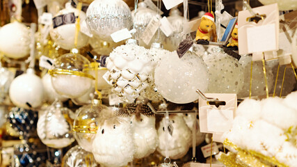 Glass Christmas balls and decorations. White with silver pine cone Christmas-tree decoration close-up. Sale of Christmas tree decorations at the Christmas market.