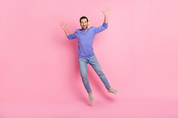 Fototapeta na wymiar Full length photo of brunet cool millennial guy jump wear headphones blue pullover jeans sneakers isolated on pink background