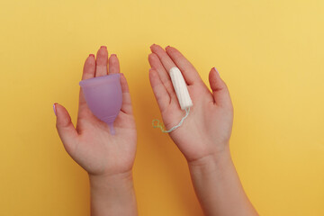 Young woman hands holding menstrual cup and tampon. Concept of women's hygiene