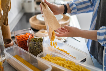 Top view female housewife placing sorting different kinds of vegan pasta into pp boxes