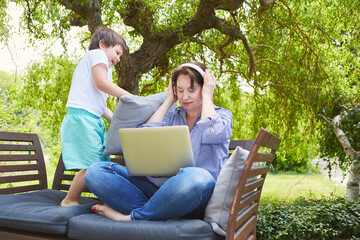 Kind nervt alleinerziehende Mutter am Laptop