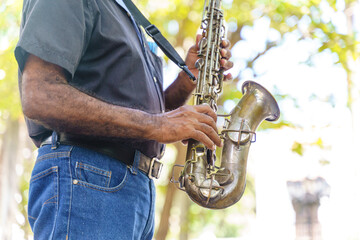 Side view of old man playing the saxophone. Horizontal detail of unrecognizable musician playing...