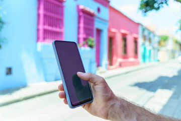 Close up view of unrecognizable man holding a phone on pink background. Horizontal view of man using cellphone isolated on pink wall. People and technology concept.