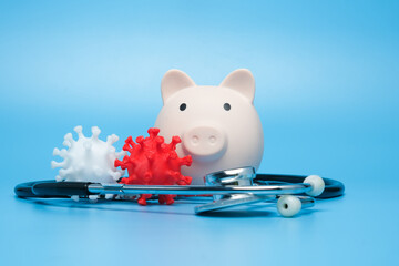 Medical Saving account affected by covid-19 concept. Selective focus of 3d printed coronavirus with piggybank and stethoscope insight.