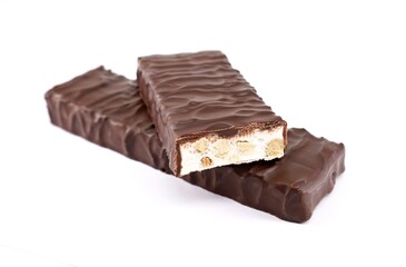 Two Torrone, one whole and the other cut, covered with dark chocolate on white background.  It is a traditional nougat of Italy	.