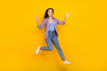 Fototapeta na wymiar Full length photo of crazy lady jump raise hands hurry run wear plaid shirt jeans shoes isolated yellow color background