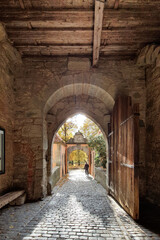 Fototapeta na wymiar старая деревянная арка с деревянными воротами и каменными стенами