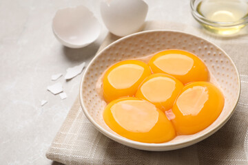 Bowl with raw egg yolks on light grey table