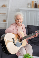 Happy elderly woman playing acoustic guitar in nursing home