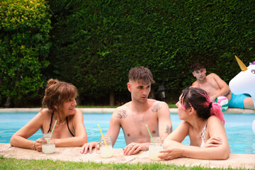 Obraz na płótnie Canvas Group of people drinking lemonade and having fun in a swimming pool.