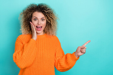 Photo of crazy lady direct finger empty space palm cheek wear orange knitted pullover isolated teal color background