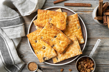 Puff dessert with raisins in a plate on a wooden light gray culinary background. Delicious homemade sweet pastries top view