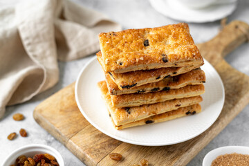 Layered dessert with raisins in a white plate on a light gray culinary background. Delicious homemade sweet puff pastry closeup
