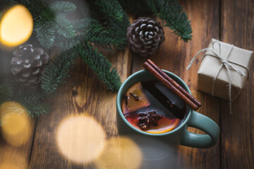 Nahaufnahme von einer Tasse Glühwein mit Zimtrinde, Tannenzweige und Lichter Bokeh. Weihnachten.