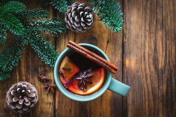 Draufsicht auf eine Tasse Glühwein mit Zimt und Orangenscheiben auf einem rustikalen Holztisch....