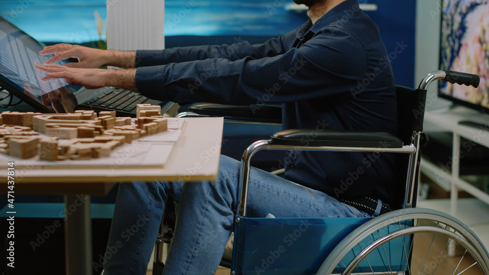 Poster architect with disability analyzing building model and using touch screen computer. invalid man work