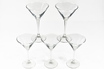 Empty martini cocktail glasses stand on top of each other on white background