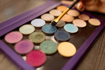 make up palette with different colors of eyeshadow, and a brush