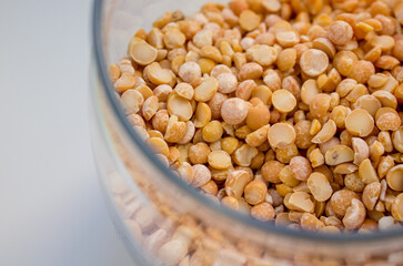 close-up dried yellow peas in a transparent glass jar