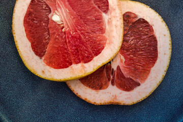 two slices of juicy pink grapefruit on a dark blue ceramic plate
