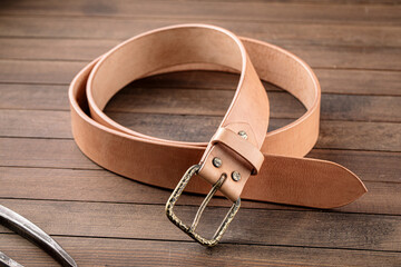 Handcrafted light brown leather strap belt on wooden background