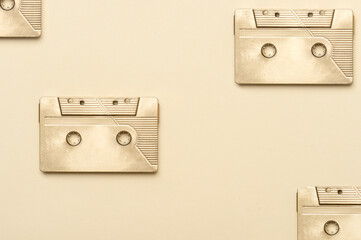 Gold fancy retro old audio cassettes tape on beige color background. Retro mixtape, 1980s pop songs...