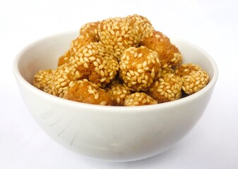 A bowl of dry and sweet Snack in the shape of a ball topped with sesame seeds.