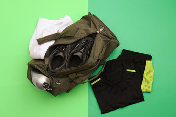 Gym bag and sports equipment on green background, flat lay