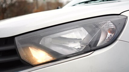 A car headlight turning on and off at day time