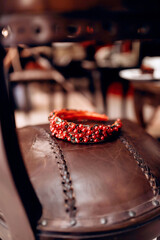 a red rim of red and transparent beads and red and green beads lies on a red leather chair