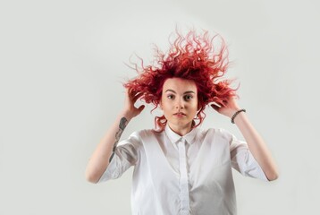 beautiful red-haired girl posing on a white background in a white shirt with emotions on her face