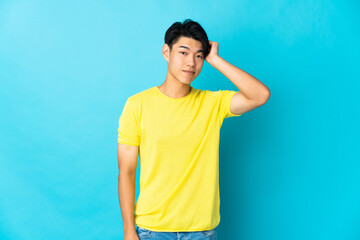 Young Chinese man isolated on blue background with an expression of frustration and not understanding