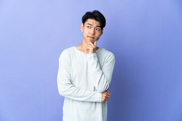 Young Chinese man isolated on purple background having doubts and thinking