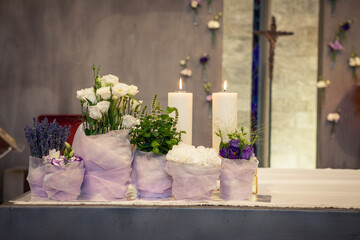 Close up view flower bags with white candles burning on altar. Church interior and set up on catholic weddings ceremony
