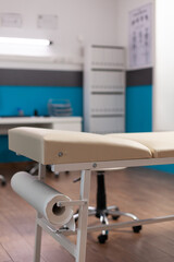 Selective focus on medical bed in empty hospital office with nobody in it during clinical consultation. Modern furniture at workplace. Bright interior of examination room. Medicine service