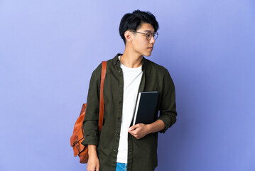 Young student woman isolated on purple background looking to the side