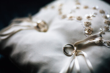 Top view two golden wedding rings with ribbons on white cushion isolated