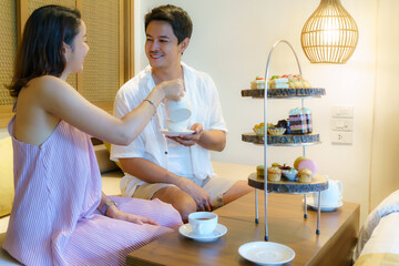 Asian couples are enjoying a romantic vacation. Having an afternoon tea set as a woman pours tea...