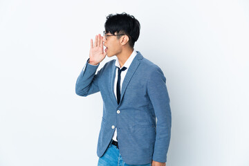 Young Chinese business man isolated on white background shouting with mouth wide open to the side