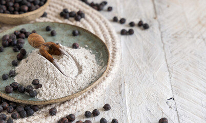 Plate and wooden scoop of black chickpea flour and beans closeup