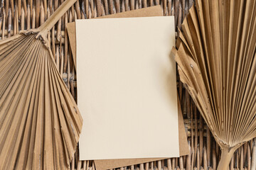 Blank card  on a wattled table with dry palm leaves