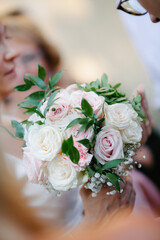 Beautiful rose bouquet in bride hands close up with people around and blurry copy paste background