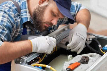 Obraz premium a man repairing a washing machine in cap