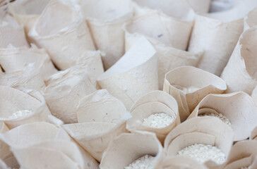 Close up top view white paper packets full of white short-grain rise for Italian wedding tradition showering newlyweds